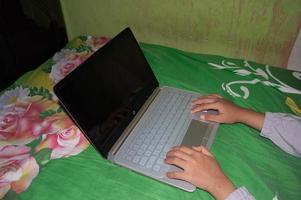 grieks, Indonesië, 2022 - een vrouw hand- spelen Aan een laptop. een vrouw werken met een laptop Aan de bed foto