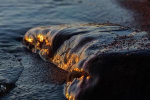 zonsondergang kleuren in de zee stenen foto