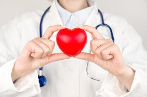 onherkenbaar dokter Holding hart Aan tafel. orgaan donaties, liefdadigheid, cardiologie concept foto