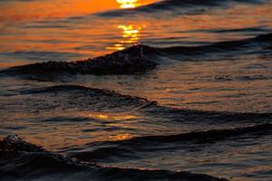 zonsondergang kleuren in de zee water foto