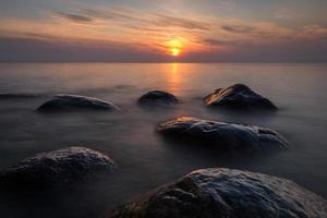 stenen Aan de kust van de Baltisch zee Bij zonsondergang foto