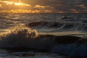 Baltisch zee kust met steentjes en ijs Bij zonsondergang foto