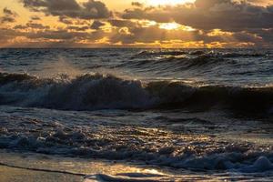 Baltisch zee kust met steentjes en ijs Bij zonsondergang foto