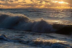 Baltisch zee kust met steentjes en ijs Bij zonsondergang foto