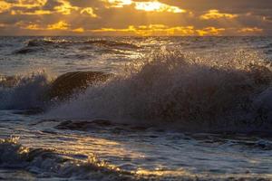 Baltisch zee kust met steentjes en ijs Bij zonsondergang foto