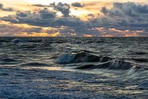 Baltisch zee kust met steentjes en ijs Bij zonsondergang foto