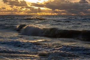 Baltisch zee kust met steentjes en ijs Bij zonsondergang foto