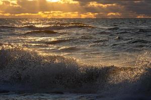 Baltisch zee kust met steentjes en ijs Bij zonsondergang foto