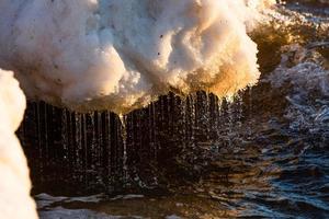 Baltisch zee kust met steentjes en ijs Bij zonsondergang foto