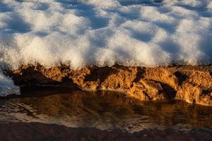 Baltisch zee kust met steentjes en ijs Bij zonsondergang foto