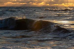 Baltisch zee kust met steentjes en ijs Bij zonsondergang foto