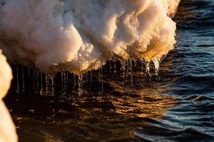 Baltisch zee kust met steentjes en ijs Bij zonsondergang foto