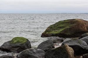 Baltisch zee kust met steentjes en ijs Bij zonsondergang foto