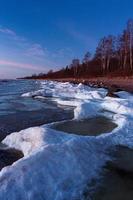 Baltisch zee kust in winter met ijs Bij zonsondergang foto