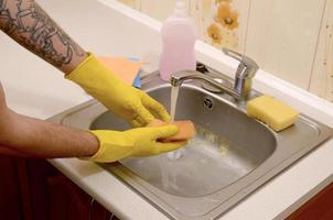 persoon of gezinshoofd schoonmaak de keuken wastafel met spons in dichtbij omhoog visie foto