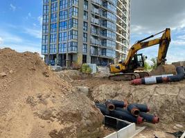 graafmachine graven de loopgraven Bij een bouw plaats. loopgraaf voor houdende extern riool pijpen. riolering afvoer systeem voor een meerdere verdiepingen gebouw. graven de pit fundament foto