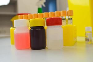 een reeks van flacon met gekleurde reagens oplossingen in een echt medisch laboratorium. achtergrond kleurrijk test buis foto
