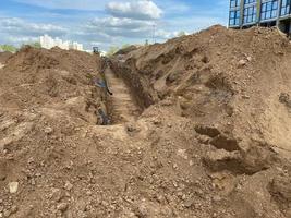 groot industrieel modern nieuw groot diameter polyethyleen plastic water pijpen liggen in een pit ondergronds Bij een bouw plaats gedurende een water pijp reparatie foto