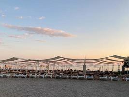 zon ligstoelen en zonnescherm met paraplu's Aan de strand Aan de zee Aan vakantie in een toerist warm oostelijk tropisch land zuidelijk toevlucht foto