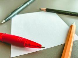 schrijfbehoeften Aan de tafel in de kantoor. twee pennen en potloden voor schrijven, schrijfbehoeften schaar liggen Aan Notitie papier. plastic pennen met houten potloden foto