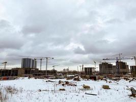 bouw van huizen, een boodschappen doen centrum van beton blokken in de stad. bouw van een nieuw woon- kwartaal in winter. hoog, meerdere verdiepingen gebouwen van een monoliet. kraan transfers platen foto