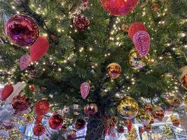 groen takken van een pluizig Kerstmis feestelijk nieuw jaar boom met speelgoed in ballen en helder gloeiend licht bollen en slingers, achtergrond foto