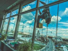 een onderhoud arbeiders schoonmaak ramen Aan hoog stijgen gebouw. foto