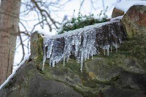 ijspegels hangende Aan de rand van de grot dak met zichtbaar wit winter lucht foto