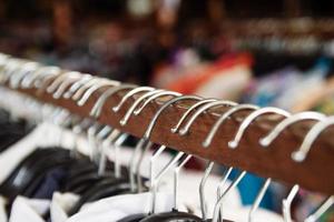 houten kleren rekken met hangers en met kleren Aan een wazig achtergrond binnen winkel. foto