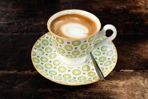 heet cappuccino in een wit-groen kop Aan een houten tafel in een cafe. foto