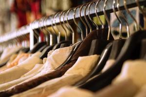 kleren rekken met hangers en met wit en bruin overhemden Aan een wazig achtergrond binnen een winkel. foto