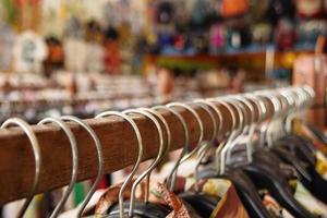 houten kleren rekken met hangers en met kleurrijk kleren Aan een wazig achtergrond binnen een winkel. foto