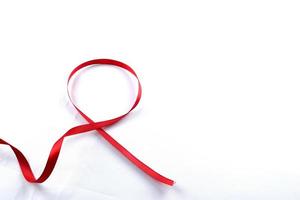 rood ondersteuning lint geïsoleerd Aan wit achtergrond. wereld AIDS dag en nationaal hiv AIDS en veroudering bewustzijn maand met rood lintje. copyspace Oppervlakte foto