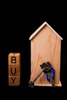 houten huis mockup met huis sleutels, houten kubussen met woorden huur uitverkoop , kopen en lening. Aan zwart achtergrond foto