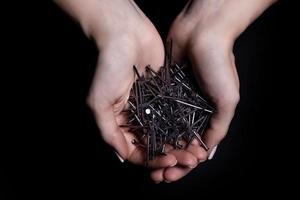 vrouw handen Holding schroeven en pluggen in handpalmen. geïsoleerd Aan zwart. vrouw handen houden schroeven nagels sluitringen noten Aan een zwart achtergrond foto