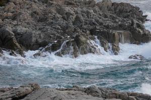 zee bereiken de rotsen creëren spatten van schuim foto