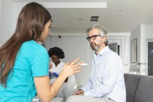 geduldig met dokter in ziekenhuis aan het wachten kamer bespreken zijn symptomen. jong vrouw dokter pratend met haar geduldig en uitleggen hem zijn opties en behandeling foto