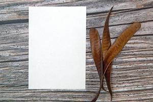 a5 papier groet kaart mockup met droog bladeren Aan houten achtergrond foto