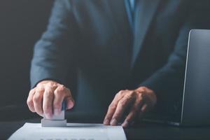 zakenman valideert en beheert bedrijf documenten en overeenkomsten, ondertekening een bedrijf contract goedkeuring van contract documenten bevestiging of garantie certificaat, goedkeuring postzegel foto