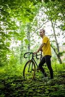 een jonge man stopte om uit te rusten met zijn fiets in een openbaar park. foto