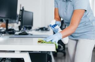 dichtbij omhoog visie van vrouw in beschermend handschoenen dat schoonmaak tafels in de kantoor foto