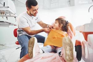 weinig meisje bezoekende mannetje tandarts in kliniek. opvatting van stomatologie foto