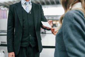 mannetje arbeider helpen vrouw. jong vrouw toerist is in de luchthaven Bij dag foto