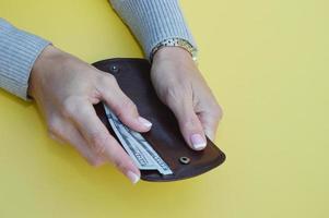 vrouwen handen zetten geld in een portemonnee. nemen uit bankbiljetten van de portemonnee. foto