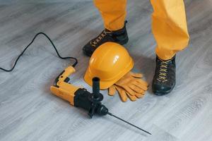 klusjesman in geel uniform met boren staand binnenshuis. huis vernieuwing opvatting foto