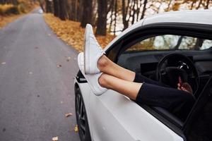 vrouw poten is uit de auto venster. modern merk nieuw auto- in de Woud foto