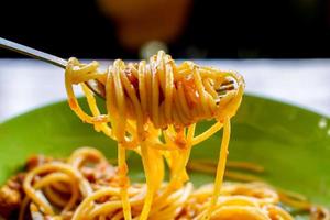 spaghetti met fijngehakt varkensvlees en tomaat saus kijken smakelijk Aan de vork. foto