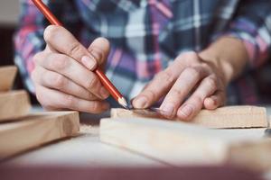 timmerman handen nemen meting met een potlood van houten plank. foto