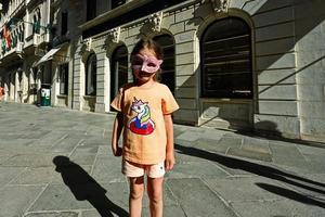 baby meisje slijtage Venetiaanse masker gesteld in straat van Venetië, Italië. foto