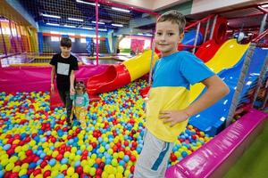 gelukkig kinderen spelen Bij binnen- Speel centrum speelplaats. kinderen in de buurt gekleurde glijbaan met ballen in bal zwembad. foto